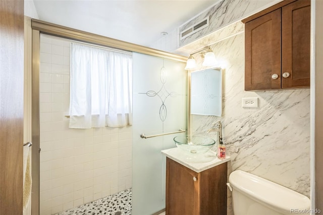 bathroom featuring tile walls, vanity, a shower, and toilet