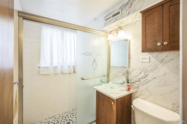 full bath featuring vanity, visible vents, toilet, and tiled shower
