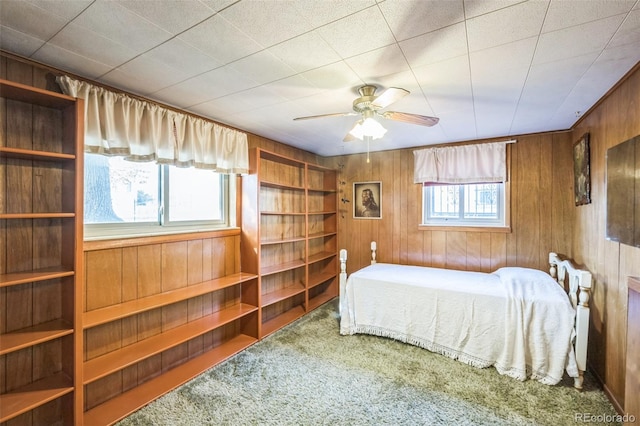 carpeted bedroom with ceiling fan and wooden walls