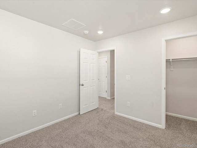 unfurnished bedroom with a closet, a spacious closet, and carpet