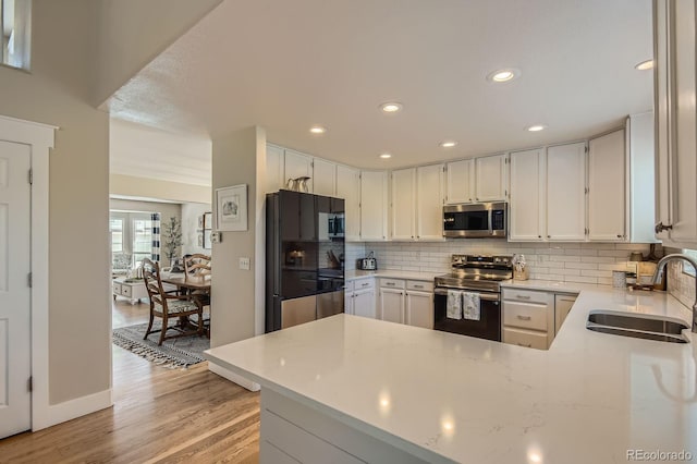 10155 Silver Maple Cir, Highlands Ranch, CO 80129 - kitchen with appliances with stainless steel finishes, a sink, backsplash, light wood-style flooring, and a peninsula