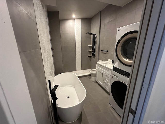 full bath with vanity, stacked washing maching and dryer, a tile shower, tile walls, and toilet