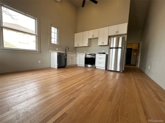 26 E Jewell Ave, Denver, CO 80210 - kitchen featuring white cabinetry, stainless steel appliances, light wood finished floors, a towering ceiling, and light countertops