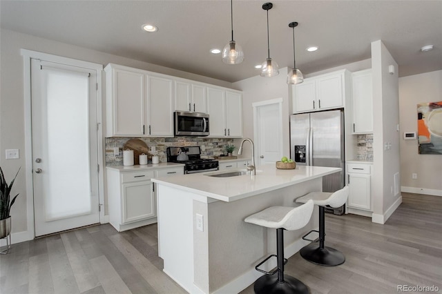 kitchen featuring an island with sink, white cabinets, sink, and stainless steel appliances