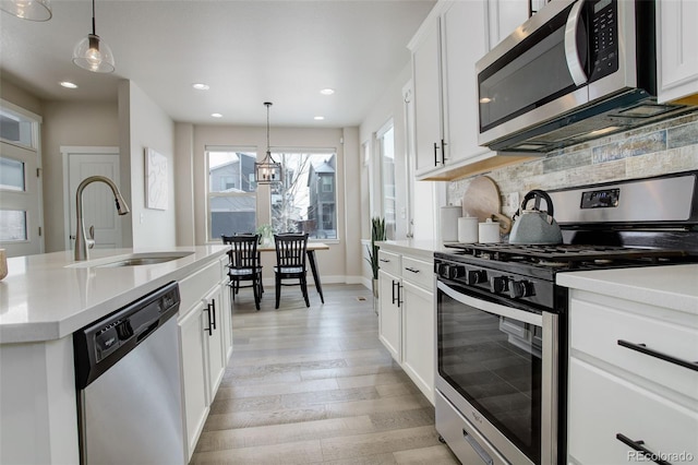 kitchen with decorative light fixtures, sink, appliances with stainless steel finishes, white cabinets, and a chandelier