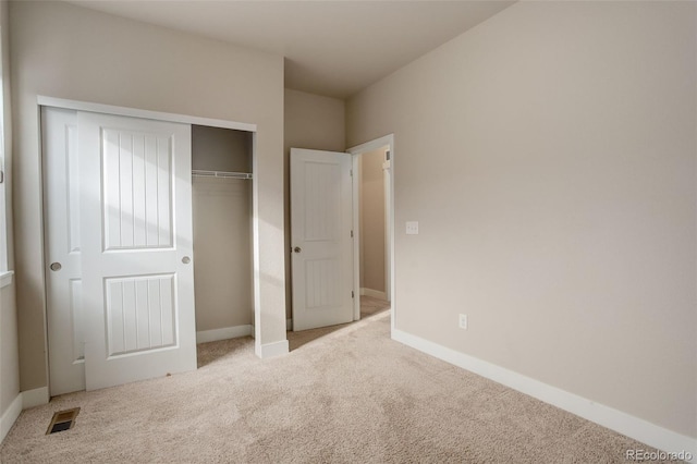 unfurnished bedroom with light colored carpet and a closet