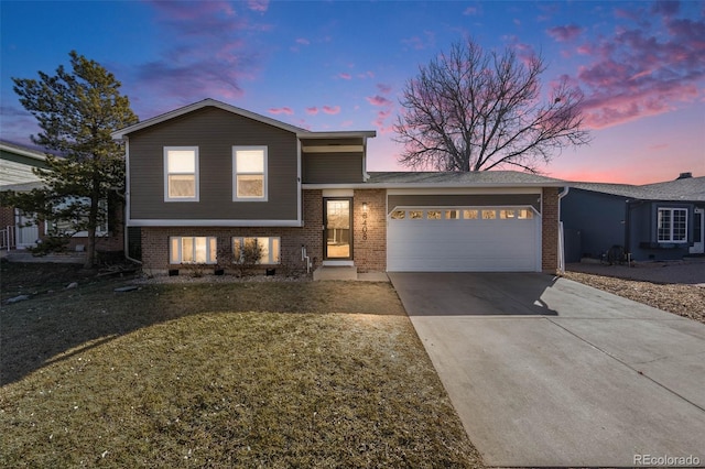 tri-level home featuring a garage and a lawn