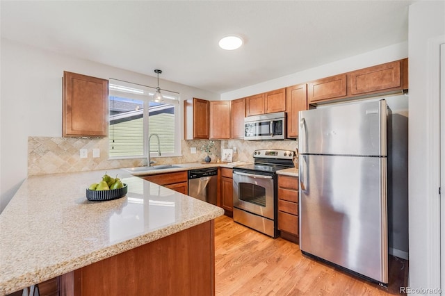 kitchen with pendant lighting, sink, stainless steel appliances, and kitchen peninsula