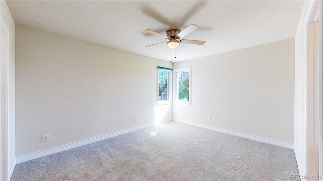 empty room with baseboards, a ceiling fan, carpet, and a textured ceiling