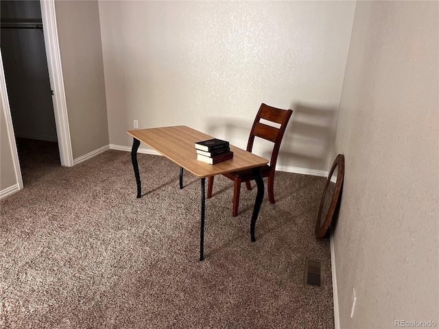 carpeted office with a textured wall, baseboards, and visible vents
