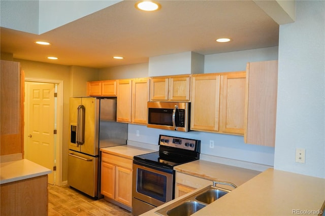 kitchen featuring light brown cabinetry, appliances with stainless steel finishes, a sink, and light countertops
