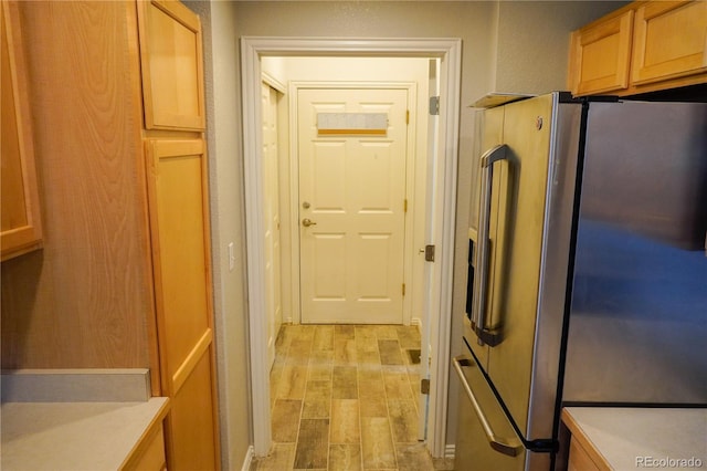 kitchen featuring light wood-style flooring, stainless steel fridge with ice dispenser, light countertops, and a textured wall