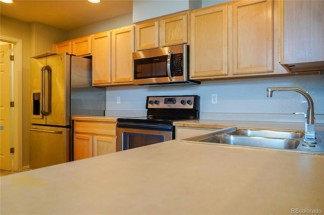 kitchen featuring recessed lighting, appliances with stainless steel finishes, light countertops, a sink, and light brown cabinets