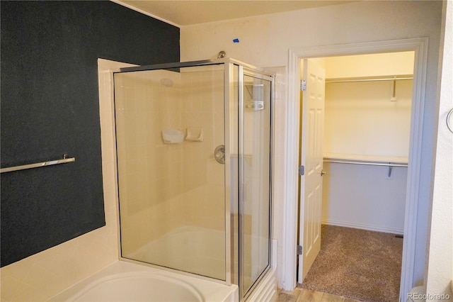 bathroom featuring a spacious closet, a stall shower, and a bathtub