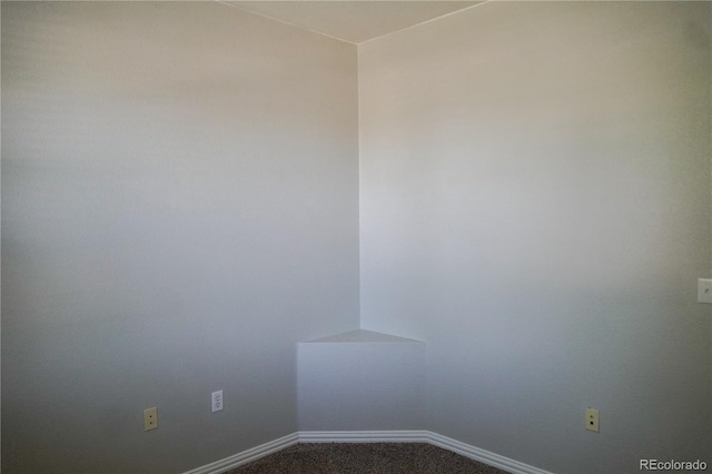 empty room with dark colored carpet and baseboards
