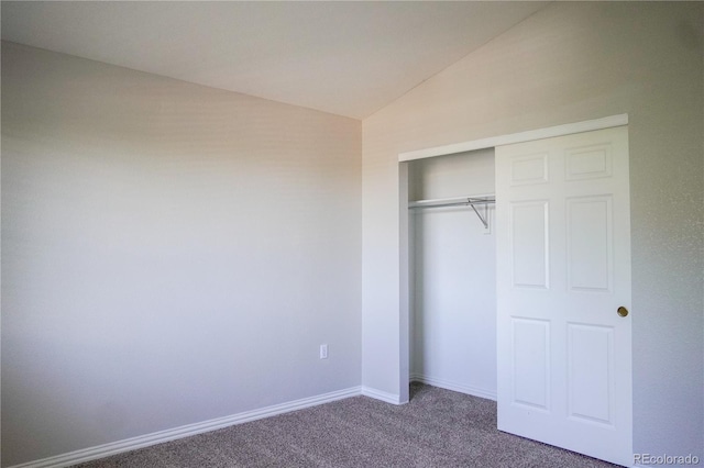 unfurnished bedroom with a closet, carpet flooring, baseboards, and vaulted ceiling