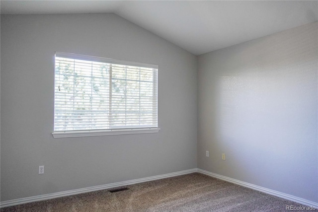 empty room featuring visible vents, carpet flooring, baseboards, and lofted ceiling