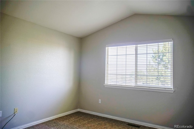 unfurnished room featuring dark carpet, visible vents, baseboards, and vaulted ceiling