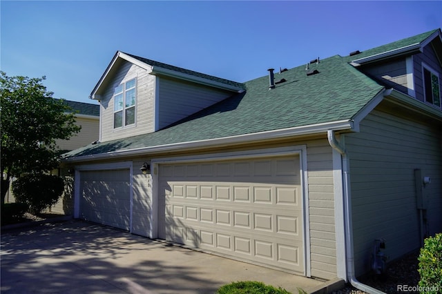 view of home's exterior with concrete driveway, an attached garage, and a shingled roof