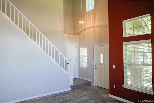 foyer with a towering ceiling, dark wood finished floors, baseboards, and stairway