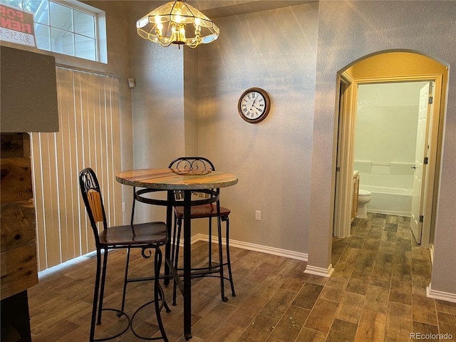 dining room featuring arched walkways, dark wood-style flooring, baseboards, and an inviting chandelier