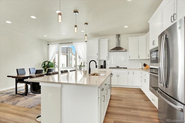 11205 W 53rd Ln, Arvada, CO 80002 - kitchen with stainless steel appliances, wall chimney range hood, a sink, light wood finished floors, and recessed lighting