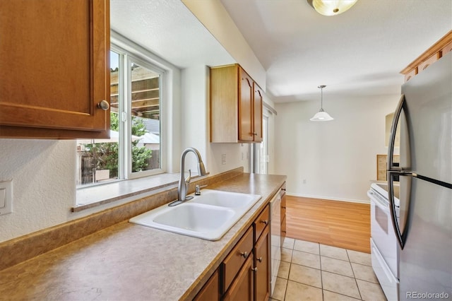 kitchen featuring hanging light fixtures, sink, light tile patterned floors, and white appliances