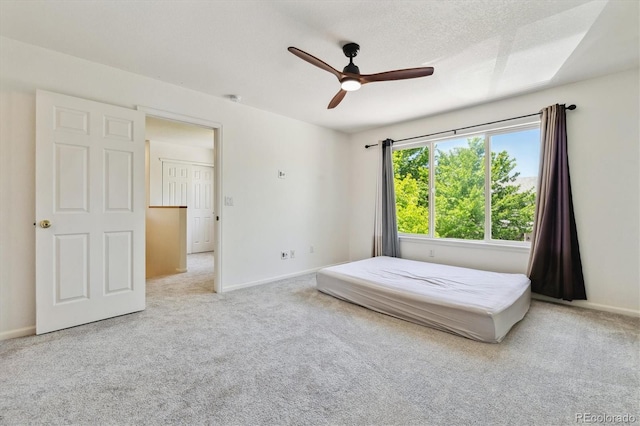 unfurnished bedroom with light colored carpet, a textured ceiling, and ceiling fan