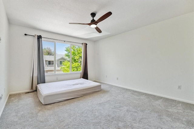 unfurnished bedroom featuring light colored carpet, a textured ceiling, and ceiling fan