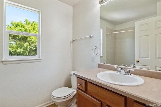 bathroom featuring tiled shower, vanity, and toilet