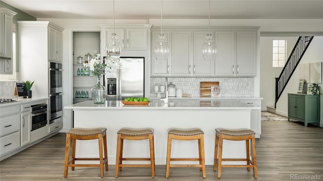 kitchen featuring a kitchen island, appliances with stainless steel finishes, and decorative light fixtures