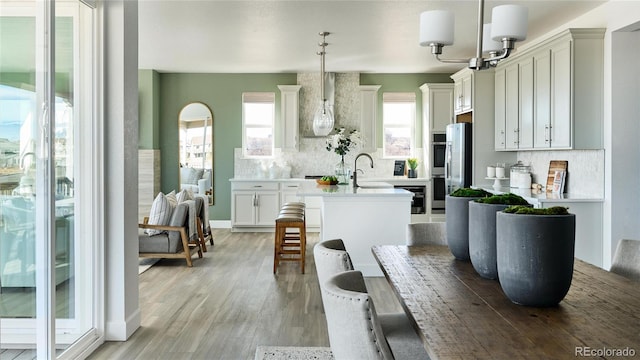 kitchen featuring decorative backsplash, a breakfast bar area, pendant lighting, light wood-type flooring, and an inviting chandelier