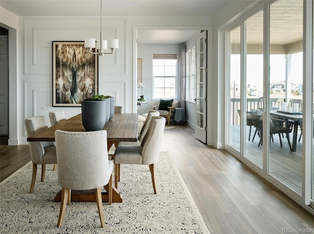 dining space with light hardwood / wood-style floors and a chandelier