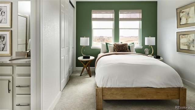 bedroom with a closet, light colored carpet, and sink