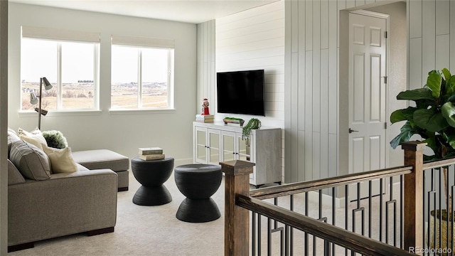 carpeted living room featuring wood walls