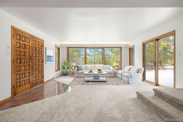 unfurnished living room featuring carpet floors, a healthy amount of sunlight, a baseboard heating unit, and baseboards