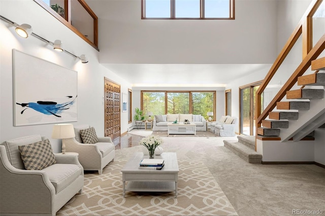 carpeted living room with stairway and a high ceiling