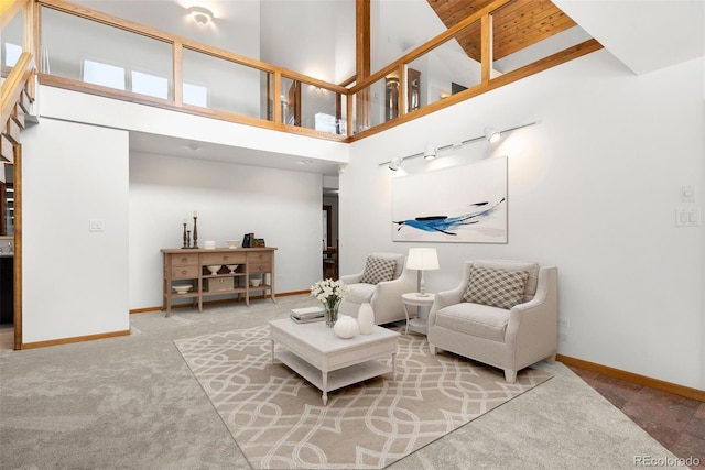 carpeted living area featuring baseboards and a high ceiling