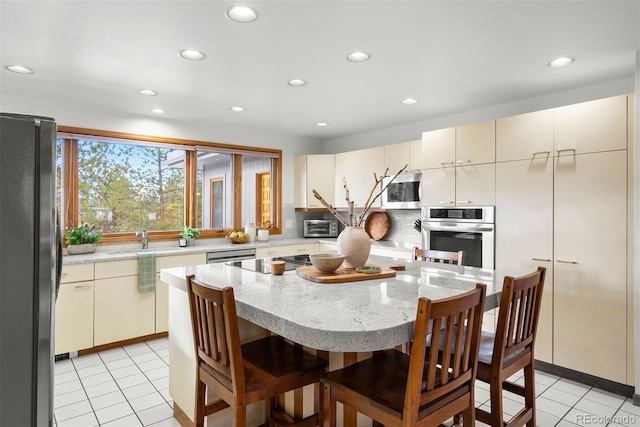 kitchen featuring stainless steel appliances, tasteful backsplash, cream cabinets, and light tile patterned flooring