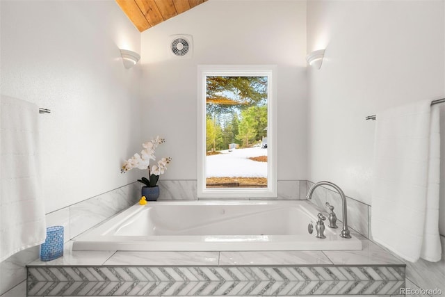 full bathroom with lofted ceiling, a garden tub, and visible vents