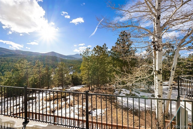 balcony featuring a wooded view and a mountain view