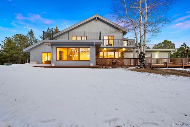 snow covered back of property featuring a balcony