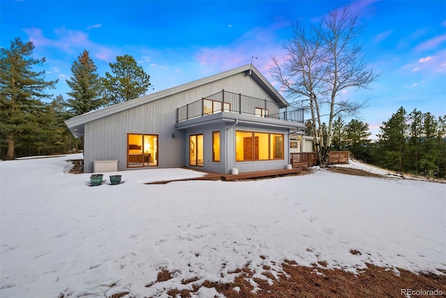 snow covered house featuring a balcony