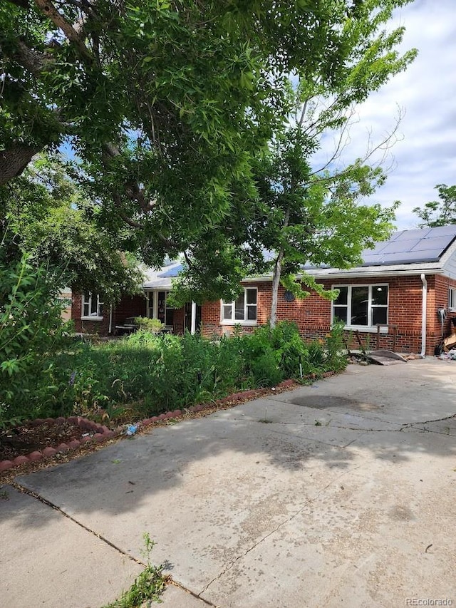 938 Salem St, Aurora, CO 80011 - view of front of home featuring brick siding, concrete driveway, and solar panels