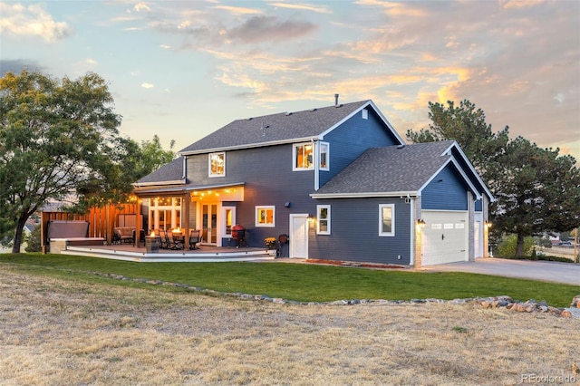 back of house featuring a garage, driveway, a lawn, fence, and a deck