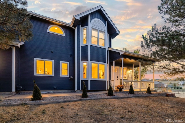 back of house at dusk with a porch