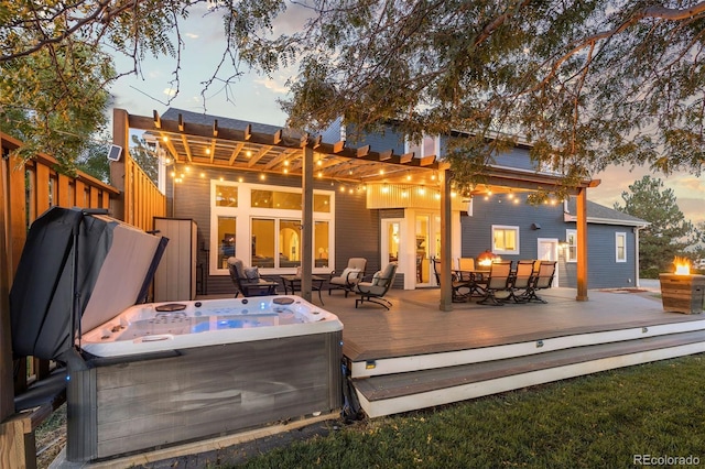 back of property at dusk featuring a deck, outdoor dining space, an outdoor fire pit, and a hot tub