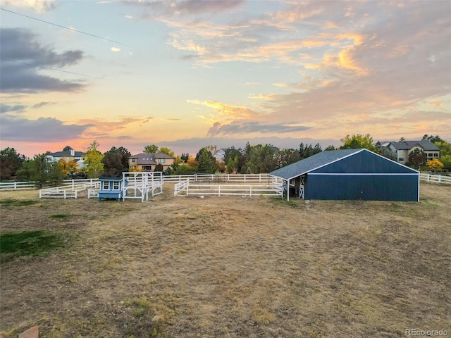 view of yard featuring a rural view, fence, an exterior structure, and an outbuilding