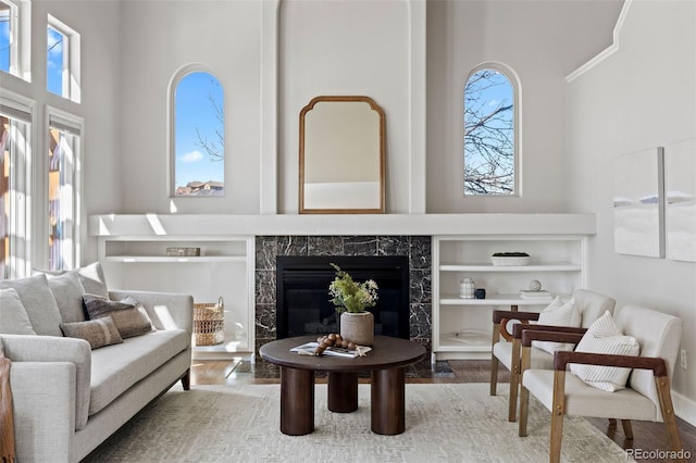 living area with a premium fireplace, built in features, and wood finished floors