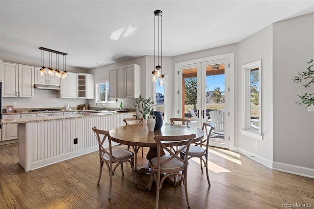 dining area with french doors, light wood-type flooring, and baseboards